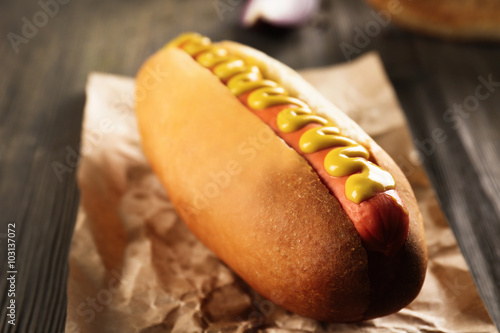 Hot dog on craft paper on wooden background