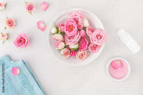 Spa settings with roses. Fresh roses and rose petals in a bowl of water and various items used in spa treatments