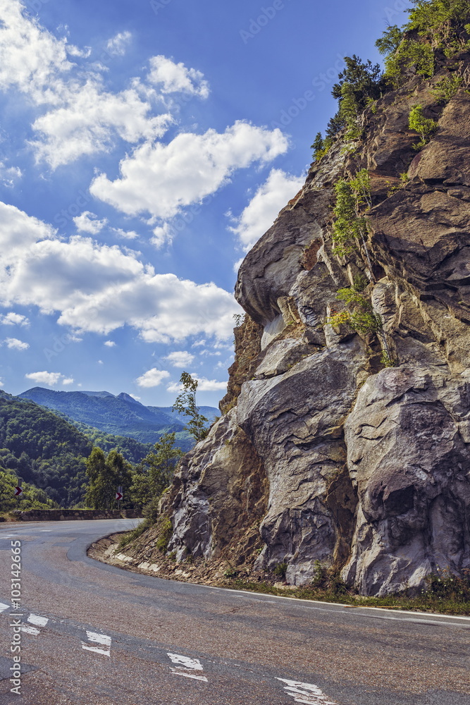 Sunny summer view with steep rocky cliff on the side of a road crossing the Siriu mountains in Buzau county, Romania.