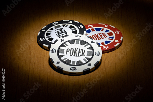 Three poker chips on the dark