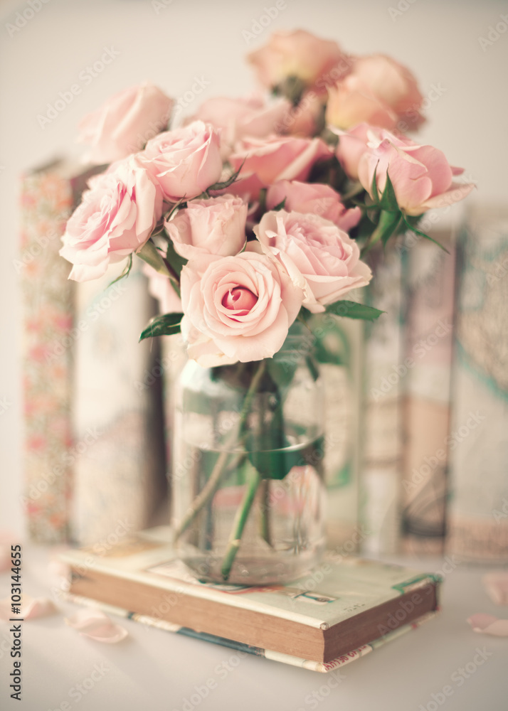 Obraz premium Roses in a crystal vase and books with vintage dust jackets
