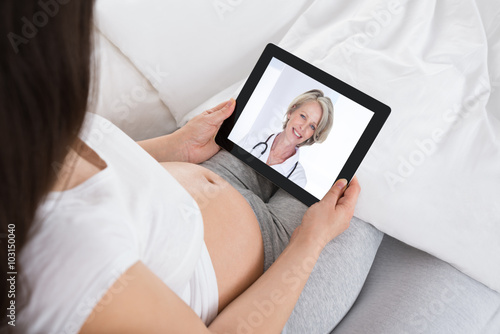 Expecting Woman Talking To Doctor On Digital Tablet