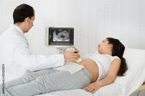 Doctor Performing Ultrasound Scan On Expecting Woman