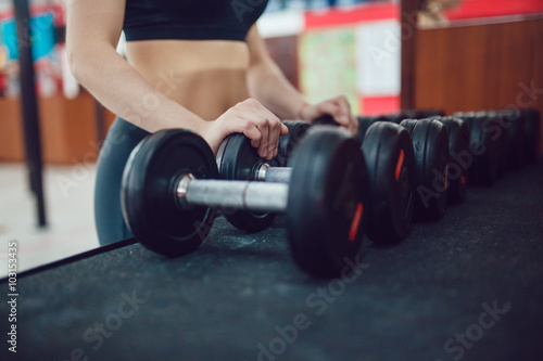 Sport girl is preparing for the exercise with dumbbells