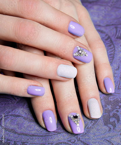 Beautiful purple manicure with crystals on female hand. Close-up. 