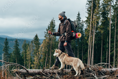 hiker with siberian husky dog looking at beautiful view in mountains