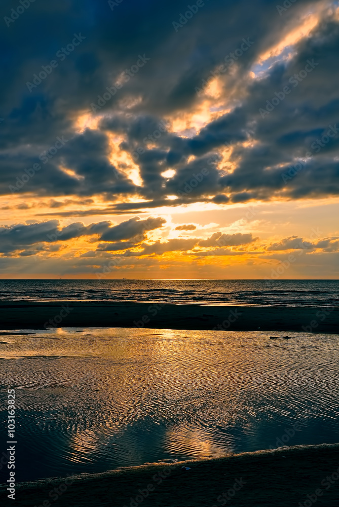 Baltic sea. Golden sunset on the sea. Coastal landscape with setting Sun reflections on the water and sand
