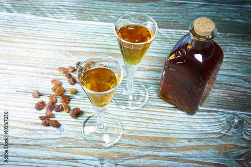 Close-up of glasses of cognac, bottle and raisin photo