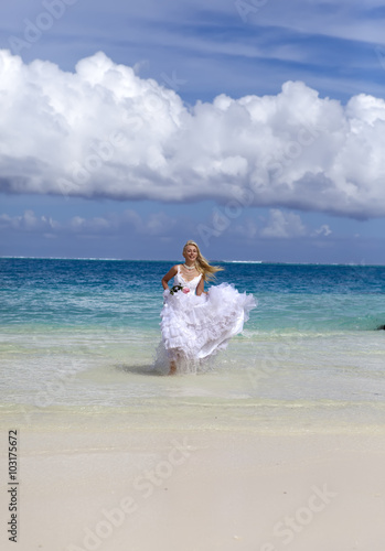 beautiful woman in a wedding dress runs on waves of the sea