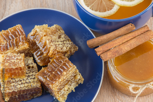 Pieces of golden honey comb on a table with tea, lemon and cinna photo