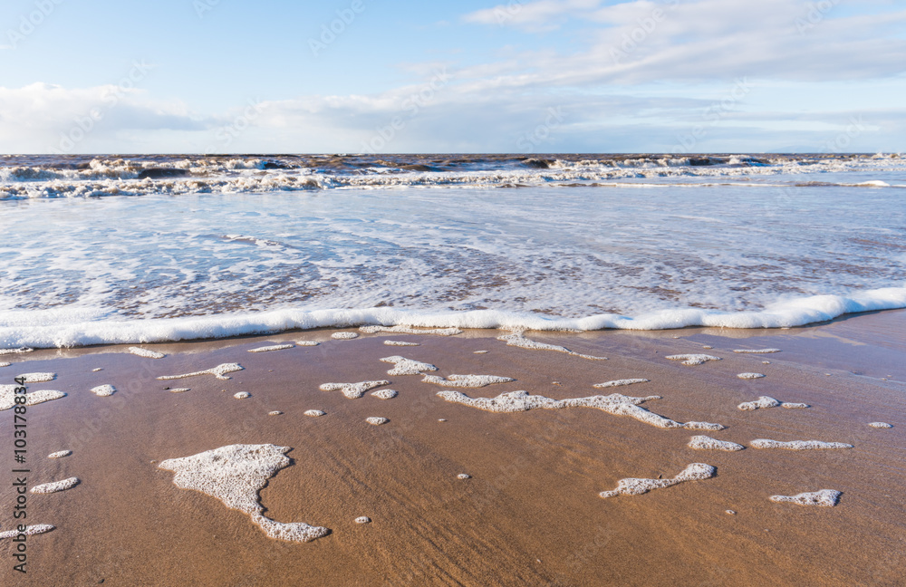Fototapeta premium relaxing and gentle calming waves flowing into a beach at sundown
