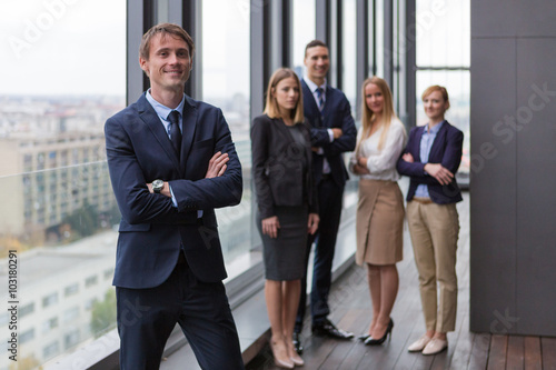Corporate portrait of young businessman with his colleagues in background.
