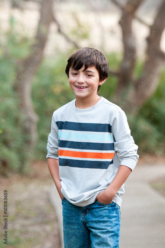Smiling Cute young boy standing on sidewalk looking at camera Smiling Cute young boy standing on sidewalk looking at camera