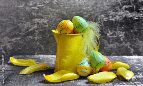 petit arrosoir jaune et œufs de Pâques décoratif  sur fond bois