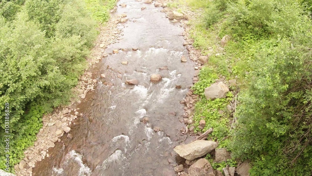 Top view of the river current in the middle of the forest in the mountains