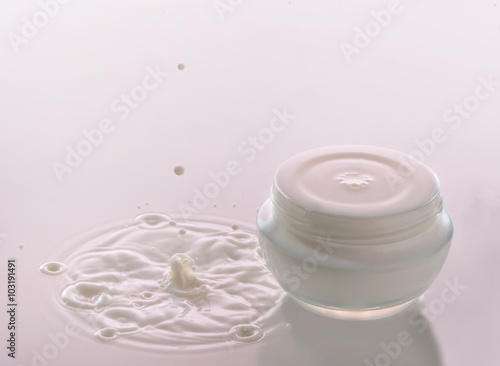 Fototapeta Naklejka Na Ścianę i Meble -  Moisturizing cosmetic  cream  stands on the pink milk background with milk splash and  falling drops