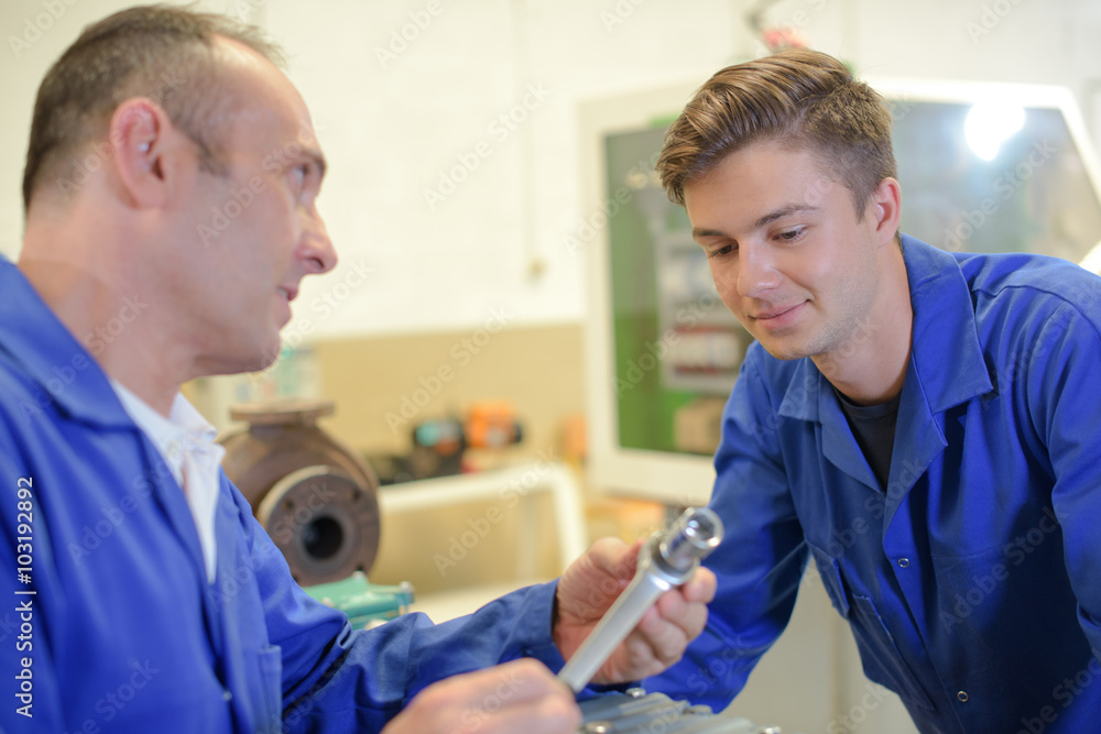Man showing socket wrench to trainee