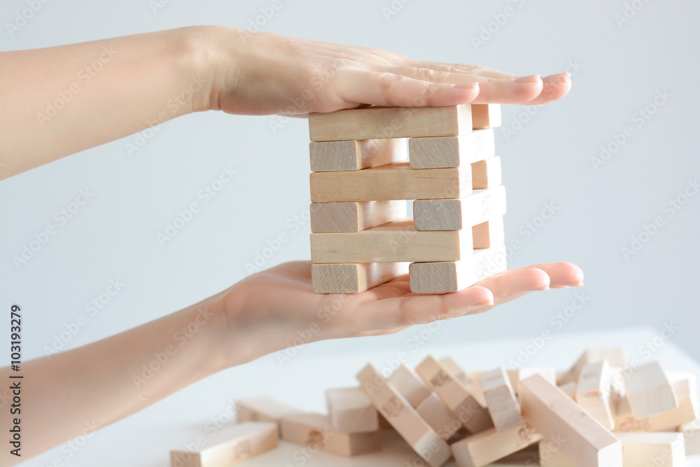 Security or insurance concept with hands protecting construction made from wooden blocks Security or insurance concept with hands protecting construction made from wooden blocks