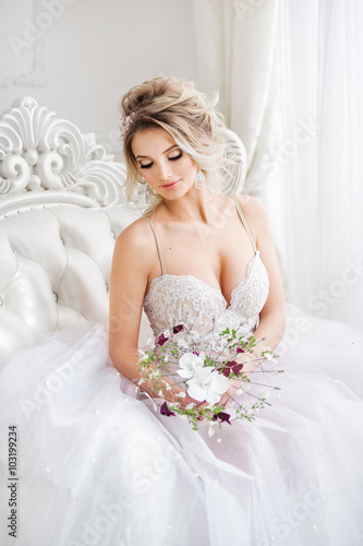 Young bride is sitting in white armchair