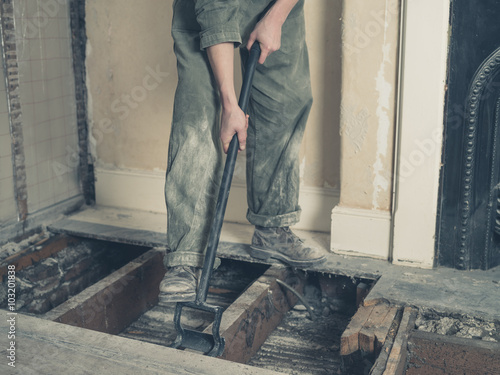 Young woman in boiler suit removing floor boards photo