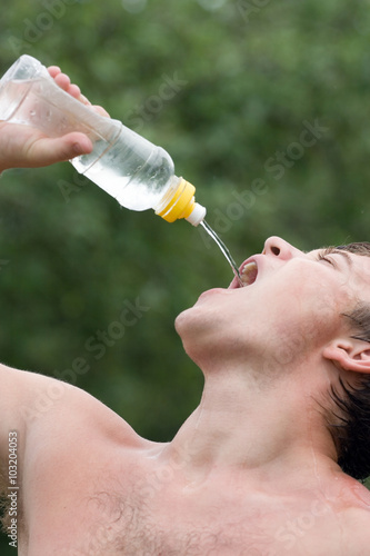 The boy is drinking water in the hot summer