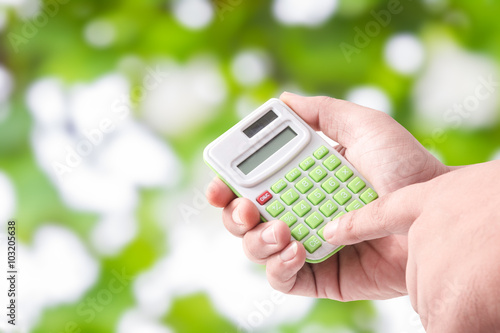 Man hand holding with calculator on Green bokeh background