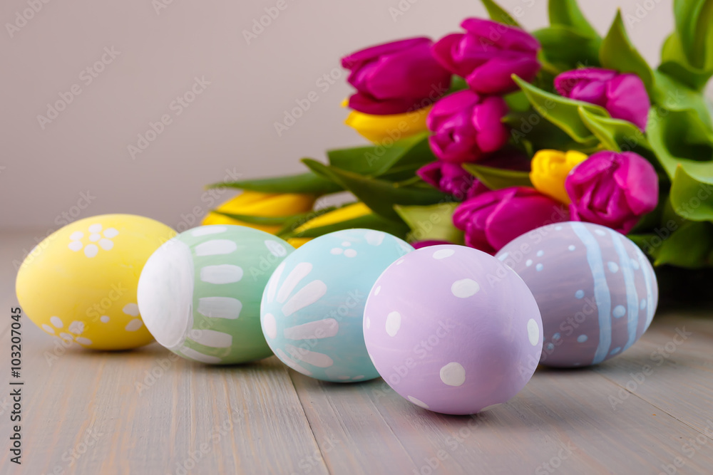 Easter painted eggs on wooden light background with spring bouquet tulips Easter painted eggs on wooden light background with spring bouquet tulips