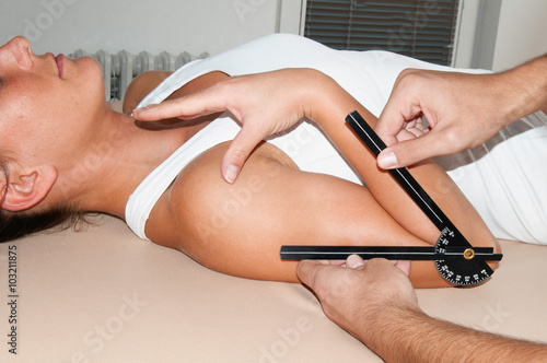 Foto Physical therapist measuring elbow flexion with goniometer