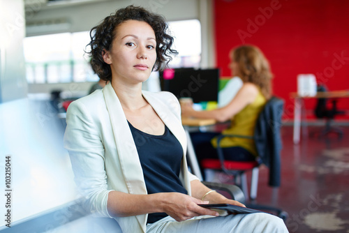 Confident female designer working on a digital tablet in red creative office space Free Download Confident female designer working on a digital tablet in red creative office space - GFXLoad