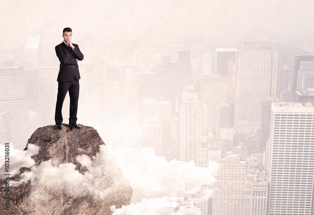 Happy businessman standing on stone top Happy businessman standing on stone top