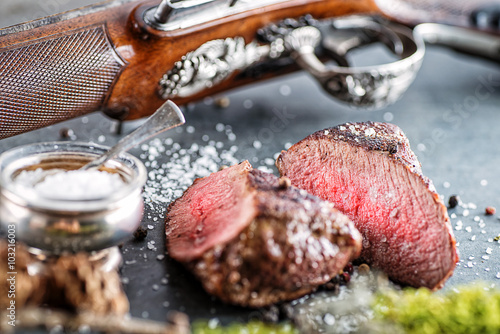 Canvastavla deer or venison steak with antique long gun and ingredients like sea salt and pe