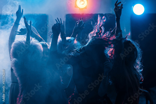 Foto party at a nightclub, young people boys and girls dancing in a smoke