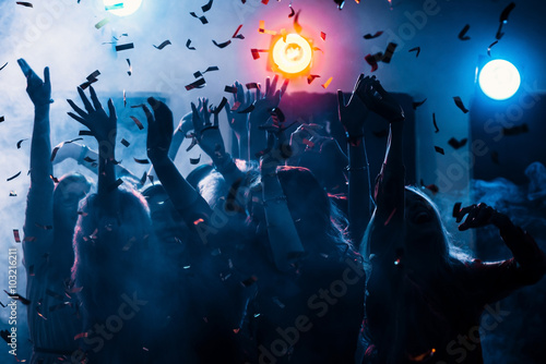 party at a nightclub, young people boys and girls dancing in smoke and confetti