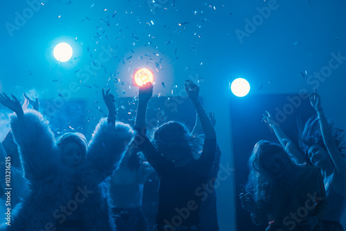 party at a nightclub, young people boys and girls dancing in smoke and confetti