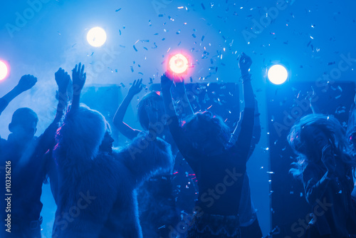 party at a nightclub, young people boys and girls dancing in smoke and confetti