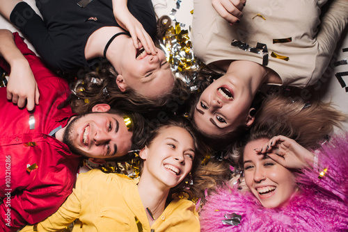 Cheerful friends lying on the floor in nightclub and looking at camera