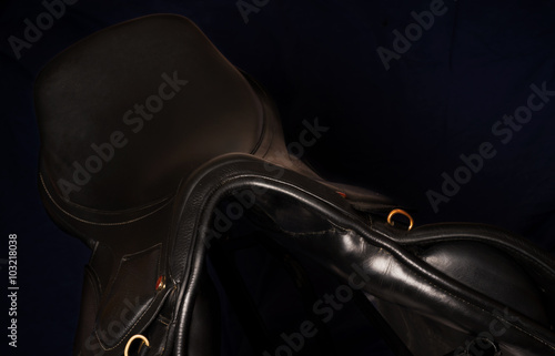 Black leather professional saddle at black background