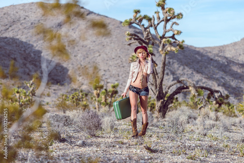 woman traveler walking with suitcase in desert