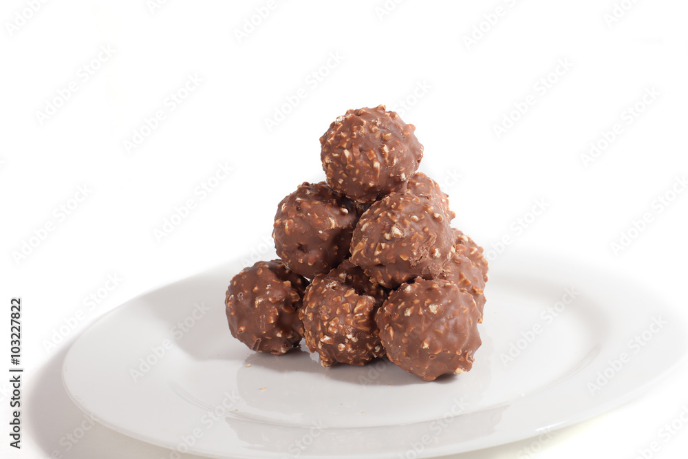 Balls of milk chocolate lie in form of pyramid on white plate Balls of milk chocolate lie in form of pyramid on white plate