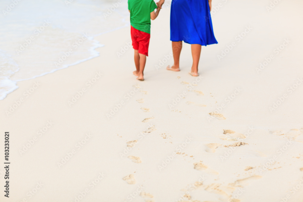mother and son walking on beach leaving footprint in sand