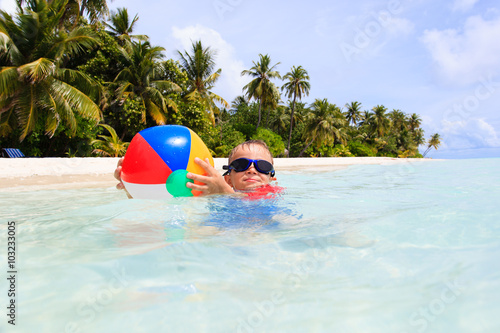 little boy playing ball on tropical beach