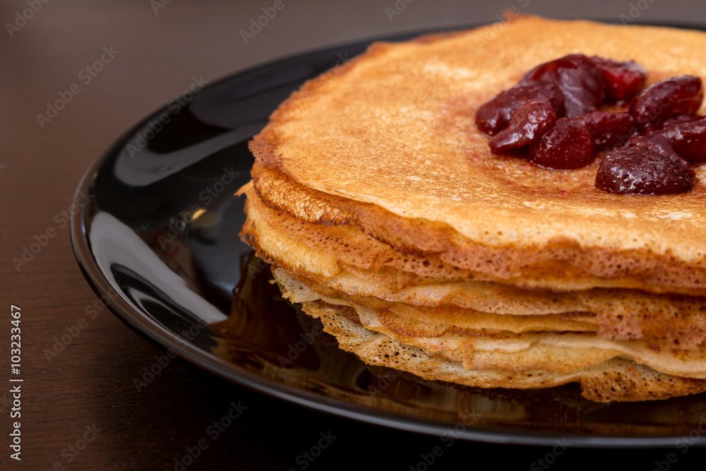Pancakes with strawberry jam on a black plate Pancakes with strawberry jam on a black plate