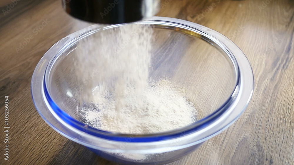 Close up of a fine curtain of refined white cake flour falling through a metal sieve Close up of a fine curtain of refined white cake flour falling through a metal sieve