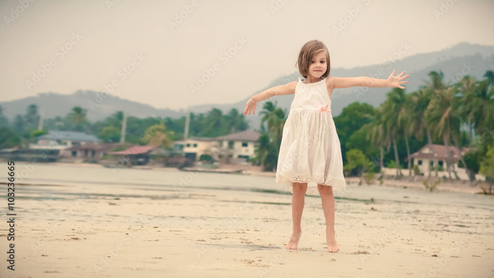 Young happy girl in white dress is expressing positivity on the tropical beach
