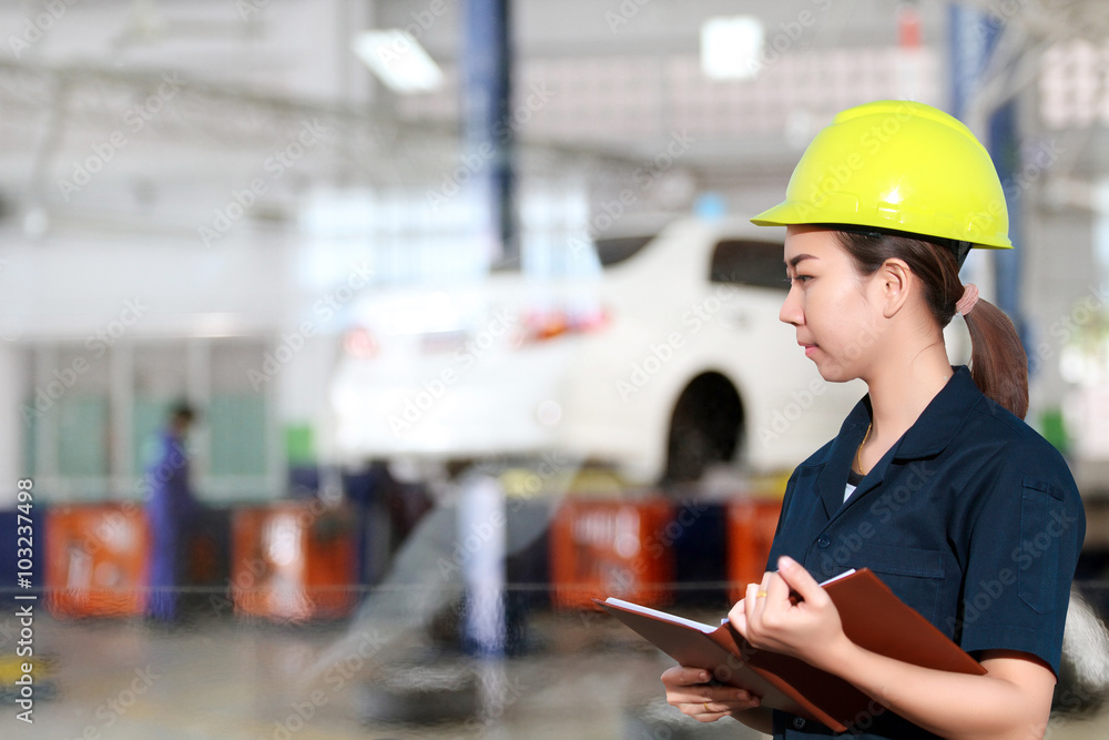 Portrait of smiling young female mechanic inspecting on a car in Portrait of smiling young female mechanic inspecting on a car in