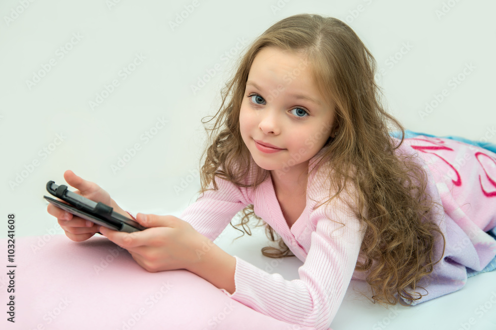 happy little girl lying on bed with tablet computer happy little girl lying on bed with tablet computer