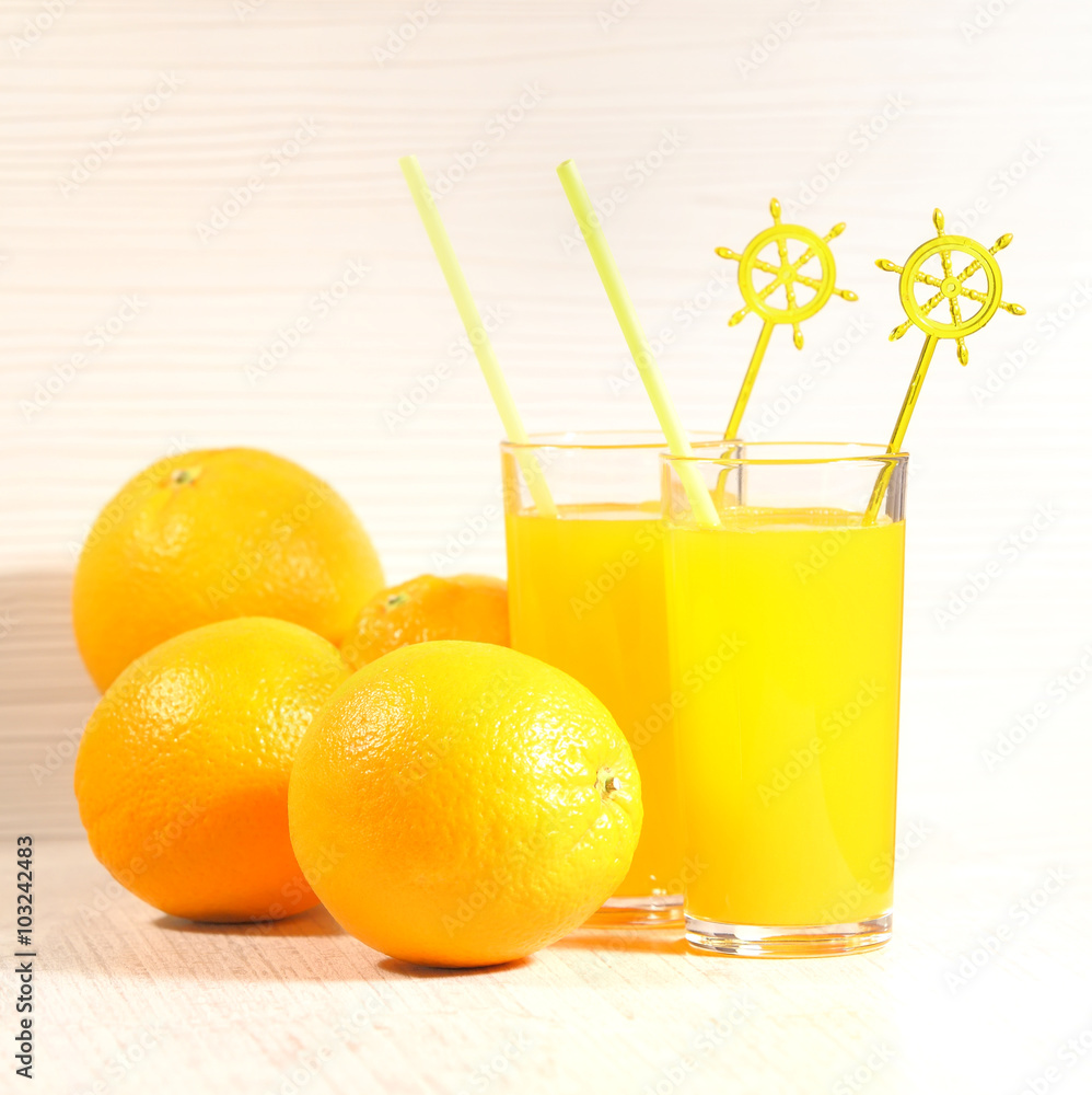 Fresh orange lemonade in a glass next to the whole fruit and orange slices on a light gray background. Selective focus Fresh orange lemonade in a glass next to the whole fruit and orange slices on a light gray background. Selective focus