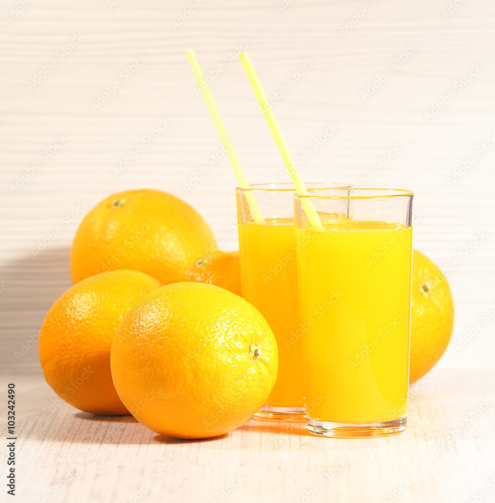 Fresh orange lemonade in a glass next to the whole fruit and orange slices on a light gray background. Selective focus Fresh orange lemonade in a glass next to the whole fruit and orange slices on a light gray background. Selective focus