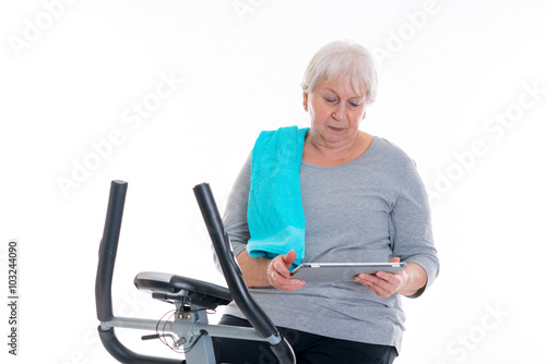 female senior train with fitness machine and using tablet PC