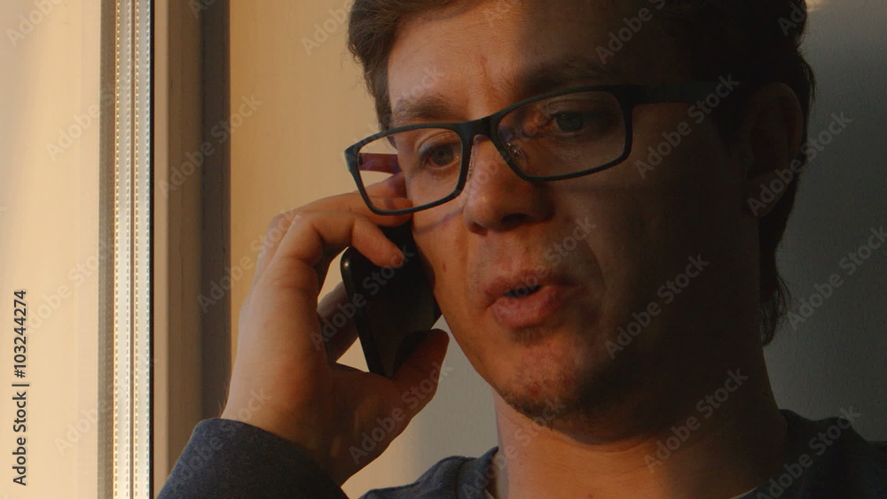 PORTRAIT: A young man talks the mobile phone near the window at the evening
PORTRAIT: A young man talks the mobile phone near the window at the evening